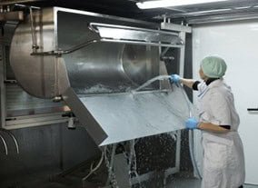 Disinfecting food processing equipment in a commercial kitchen for hygiene compliance.