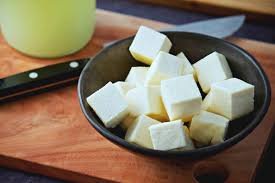 Cubed white tofu on a wooden surface, showcasing food safety handling.