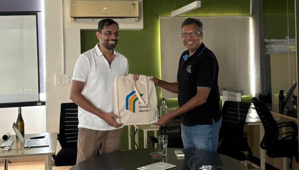 Two men exchanging a Food Safety Works bag in an office setting.