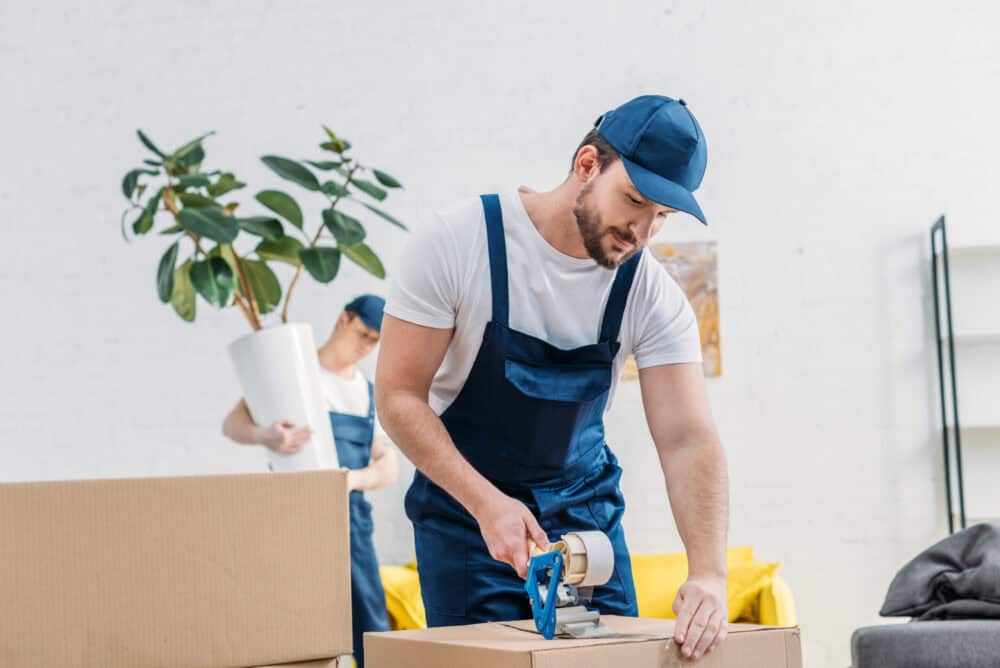 mover in uniform wrapping cardboard box with scotc 2024 11 19 17 12 53 utc scaled e1763251656762 Home
