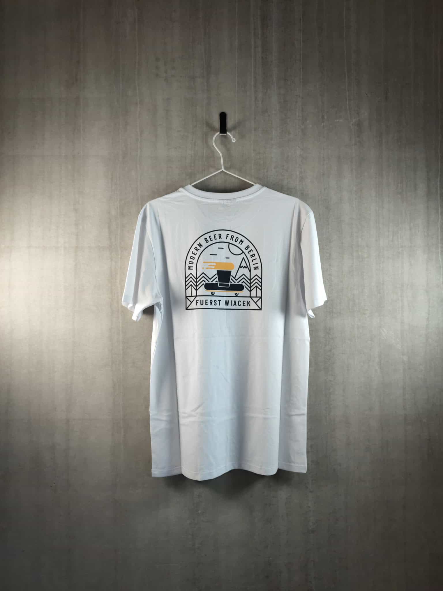 Fuerst Wiacek brewery branded T-shirt hanging on a wall with logo and design details.