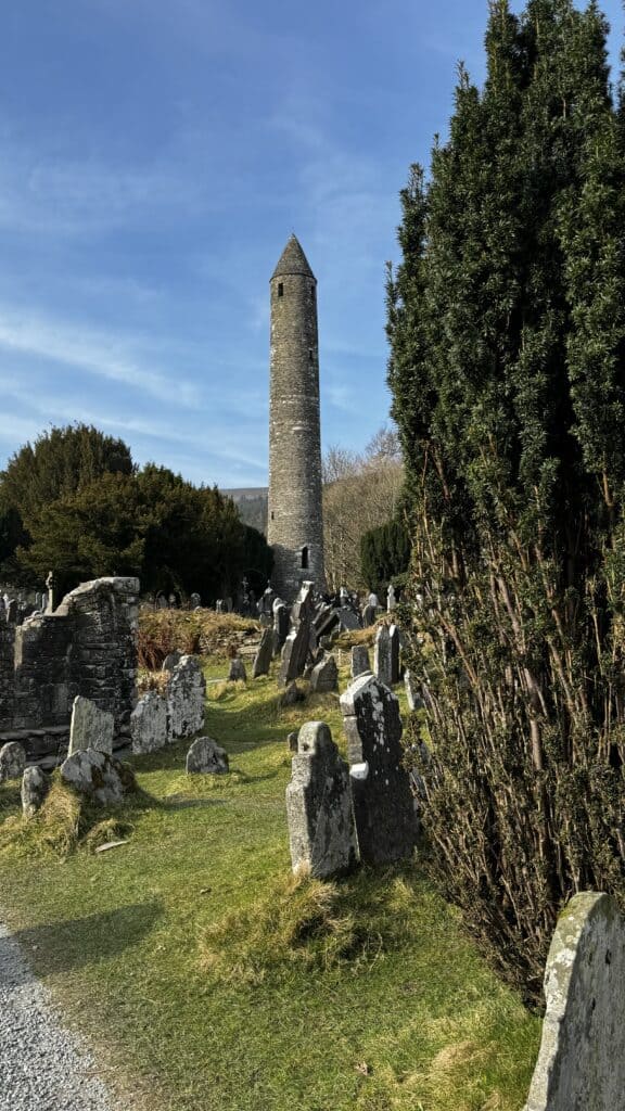 Round tower amidst graveyard and trees