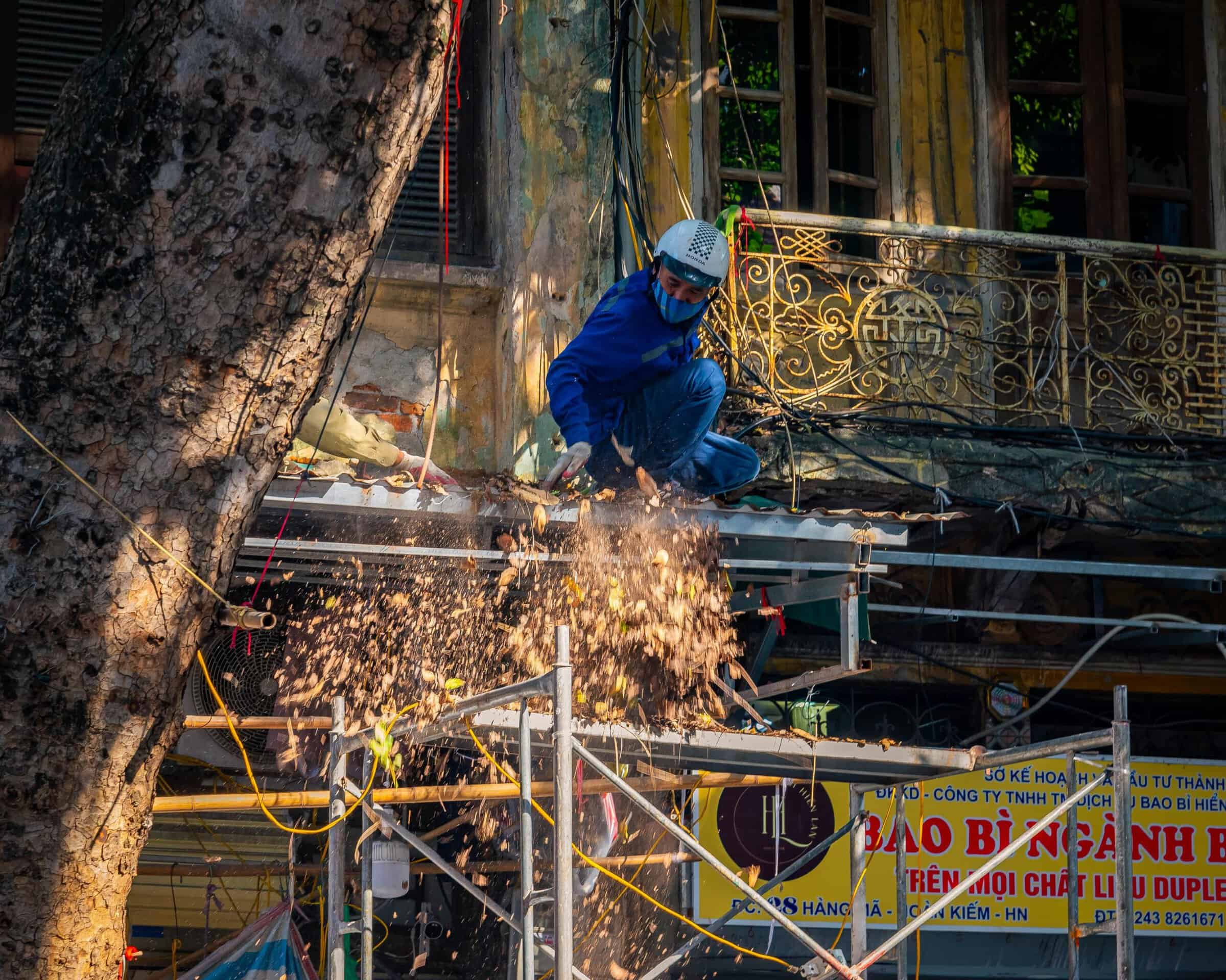 Construction worker on scaffolding with falling debris from overhead work