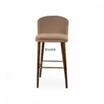 Soft beige upholstered bar stool with wooden legs and metal footrest, modern furniture for kitchen or bar area.