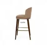 Elegant beige upholstered bar stool with wooden legs and gold footrest for modern kitchen decor.