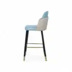 Contemporary bar stool with light blue and beige upholstery, black legs, and gold accents for modern home decor.