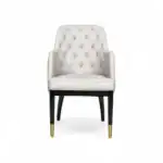 Luxurious white upholstered armchair with tufted back, black legs, and gold accents, perfect for elegant home decor.