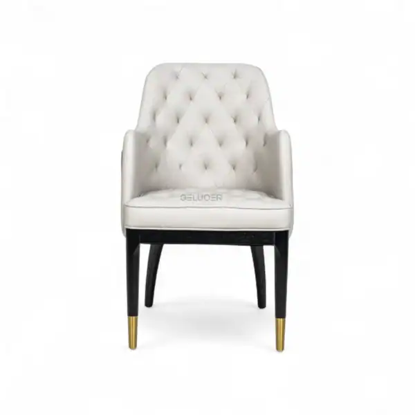 Luxurious white upholstered armchair with tufted back, black legs, and gold accents, perfect for elegant home decor.