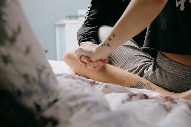 En närbild på ett par som sitter på en säng, med fokus på närhet och samtal, vilket symboliserar strävan efter djupare förståelse i en relation och att utforska "varför".
