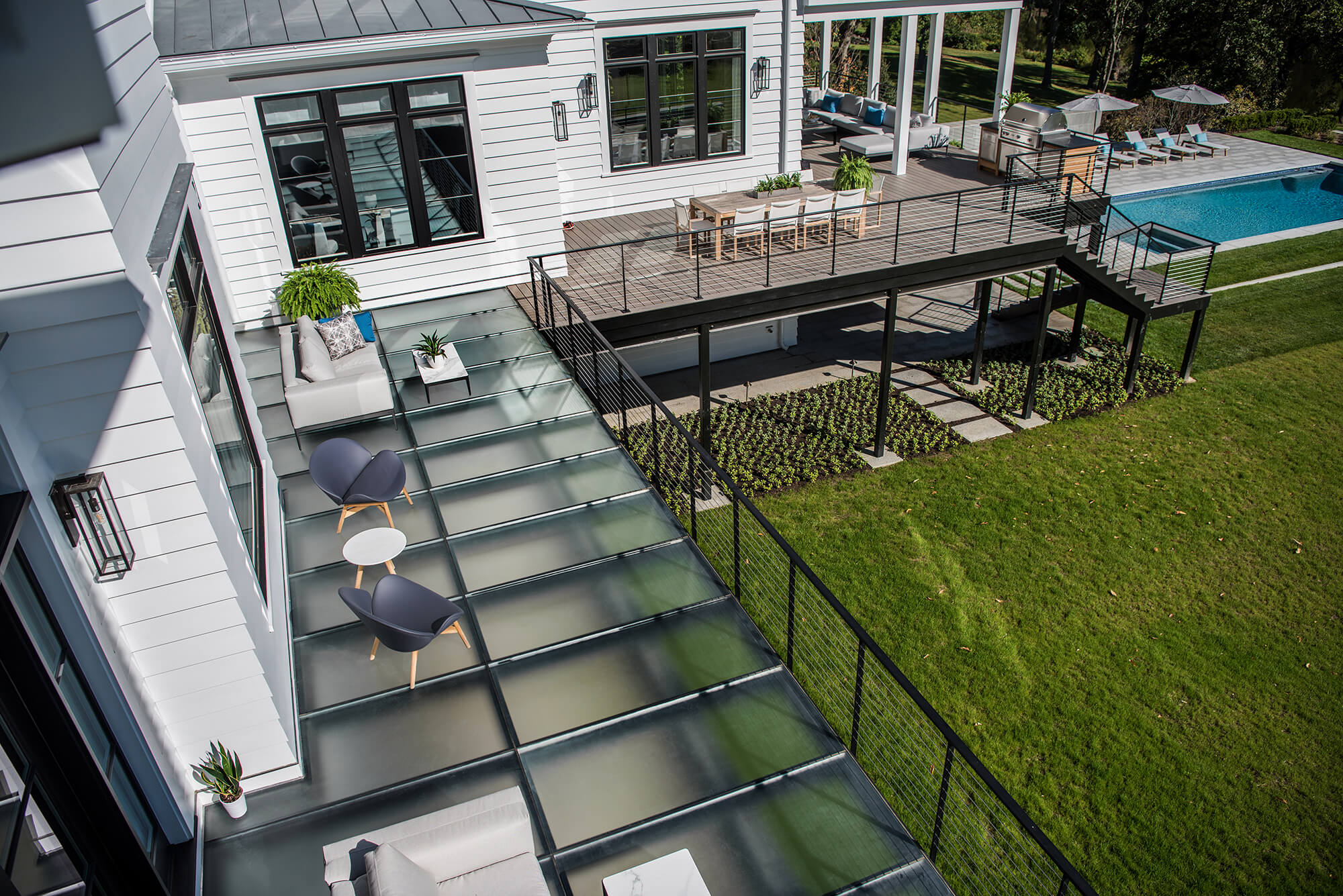 Aerial view of a residential rooftop deck built with walkable glass deck panels beside a pool