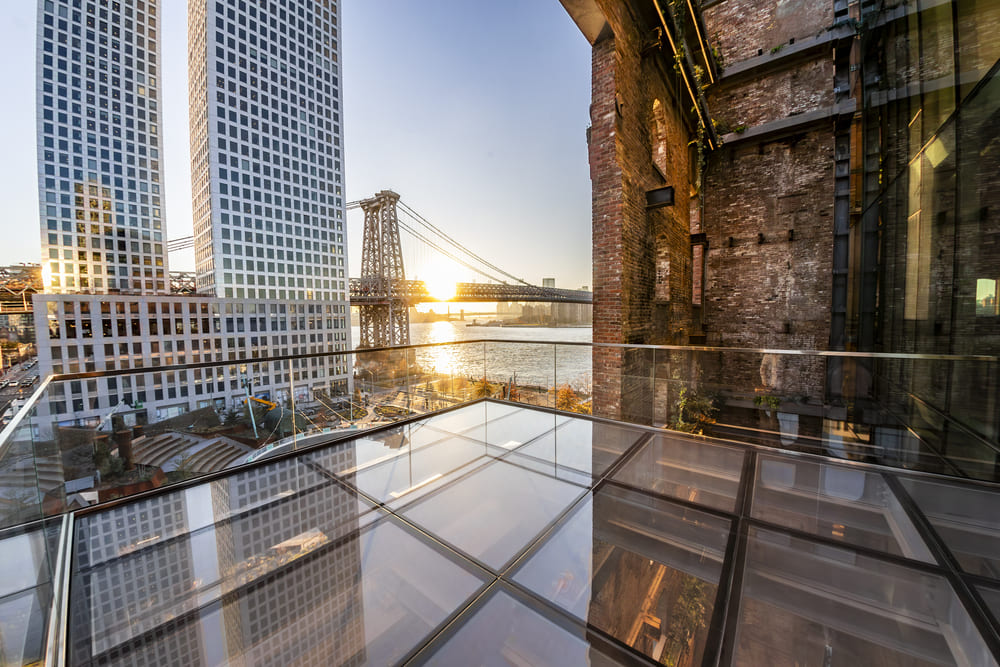 Rooftop observation deck of walkable glass panels with glass railings overlooking the Brooklyn Bridge