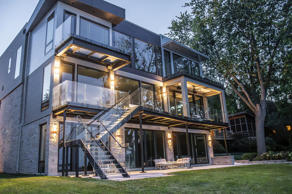 Rear of a modern home at night with walkable glass balconies and an exterior glass stair
