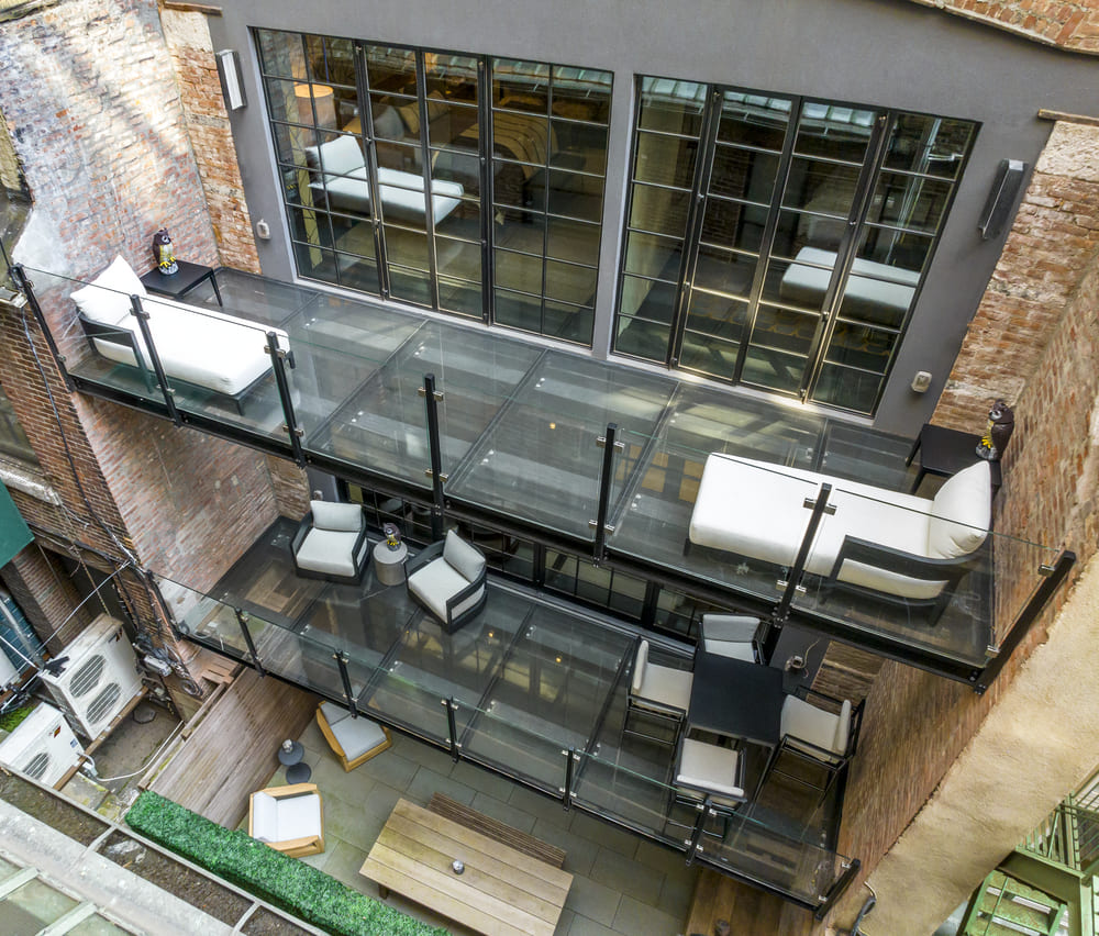 Looking down onto a walkable glass balcony with outdoor furniture