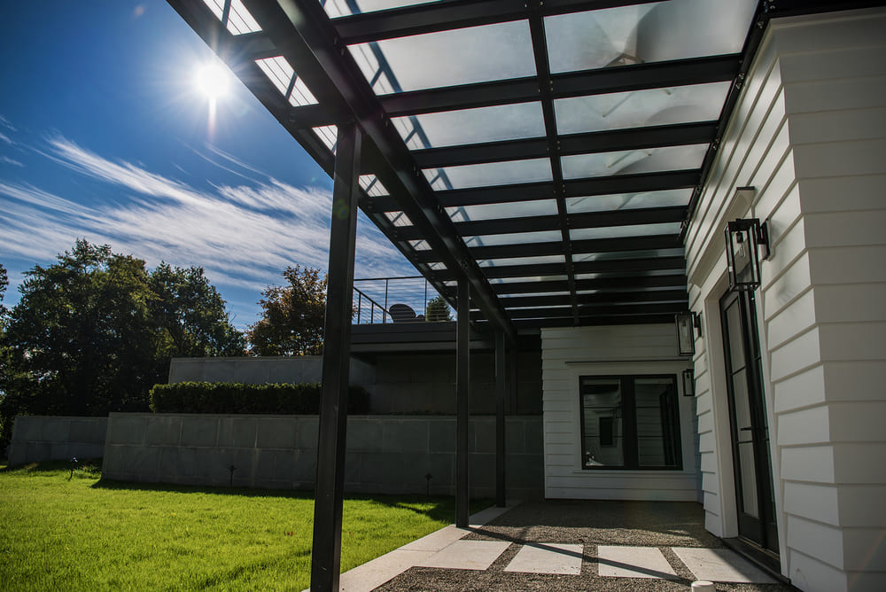 Backyard patio at night beneath a structural glass canopy
