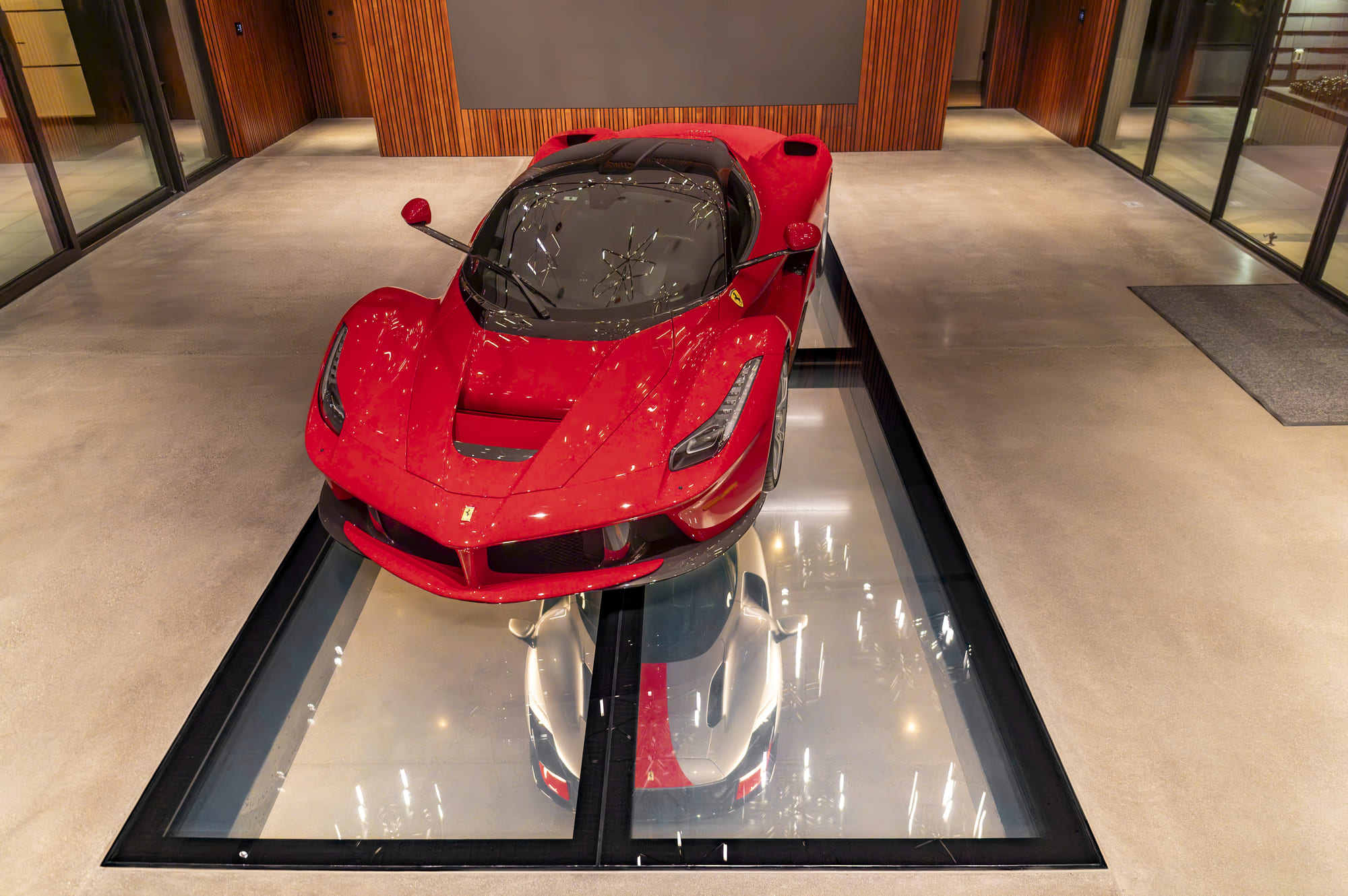 Red Ferrari displayed on a structural glass showroom floor