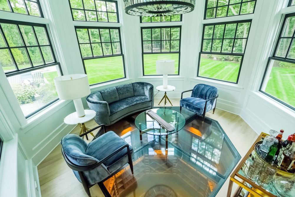Hexagonal living space with large windows and a custom walkable glass floor, velvet sofa and glass center table