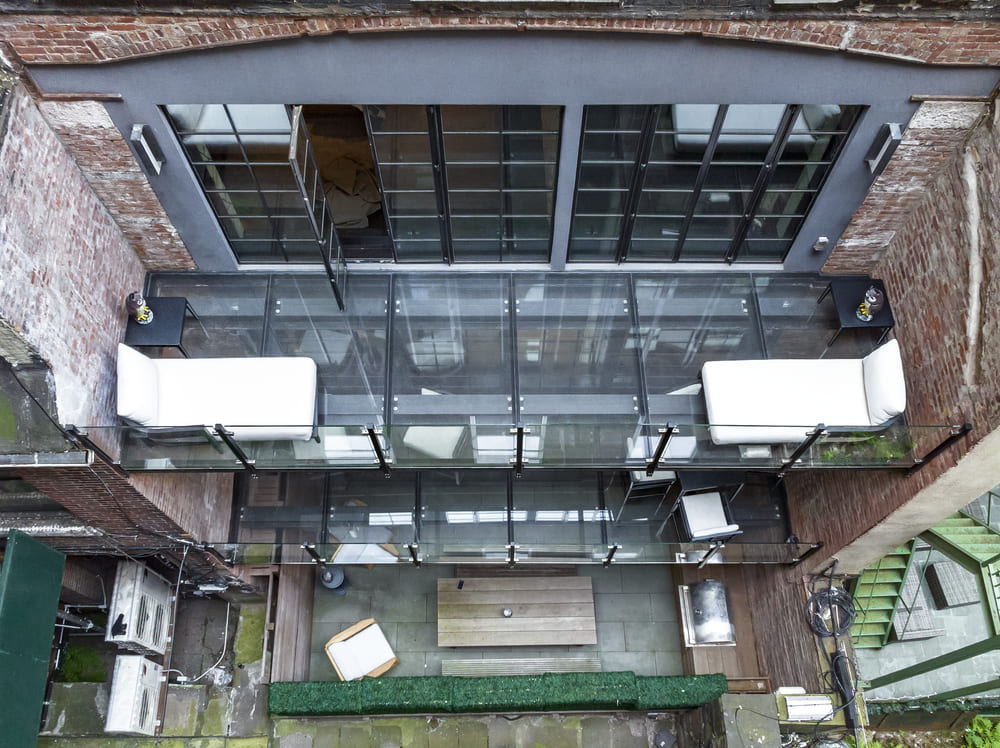 View from below of a walkable glass deck with outdoor furniture on top