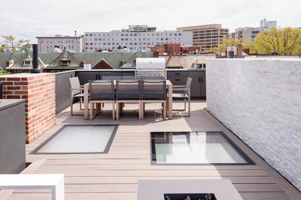 Roof deck with walkable glass skylight panels and wood decking, outdoor kitchen counter and dining table