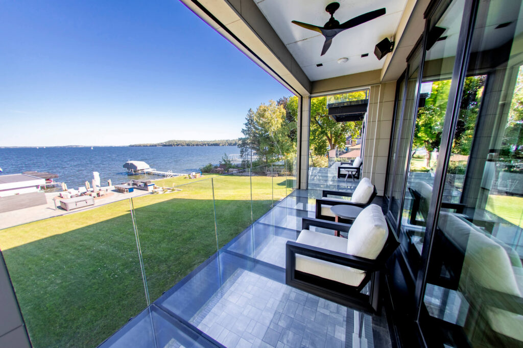 Waterfront home balcony with walkable glass floor panels and a glass railing overlooking the lake