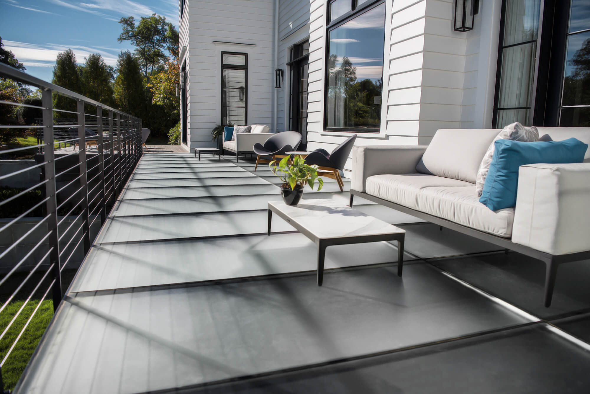 Balcony with walkable glass floor panels, a white outdoor sofa and a cable railing