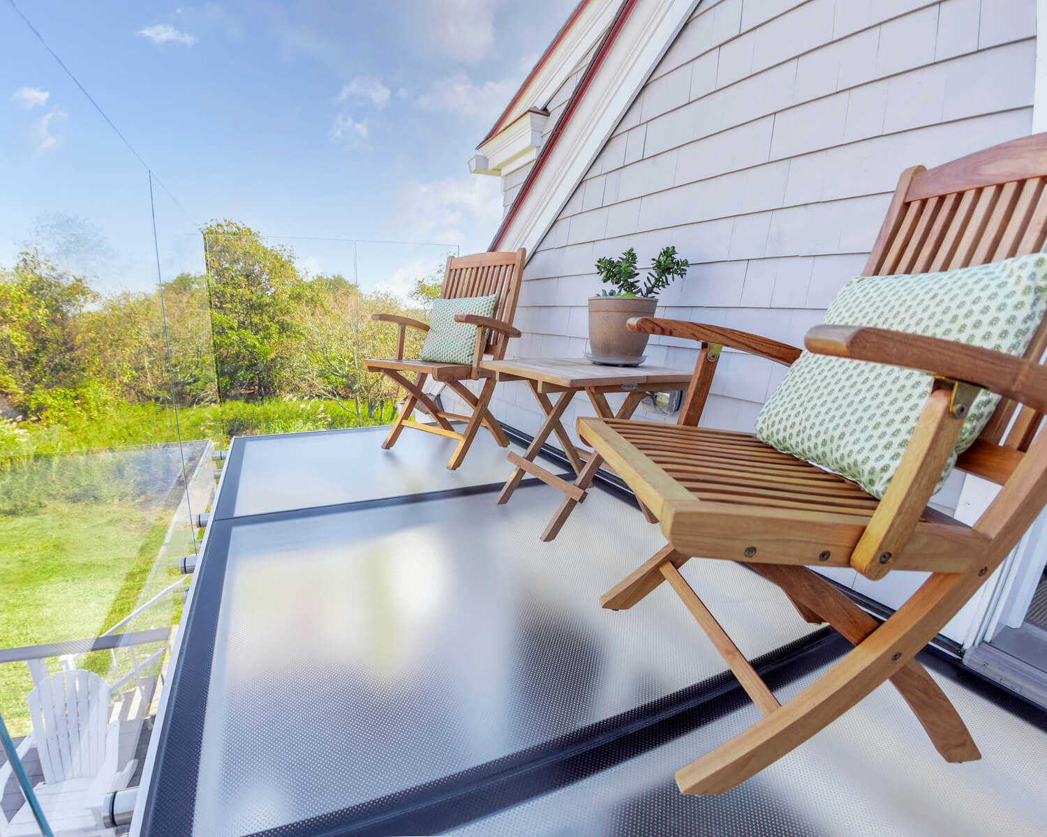 Balcony with a walkable glass floor panel and wooden patio chairs overlooking the yard