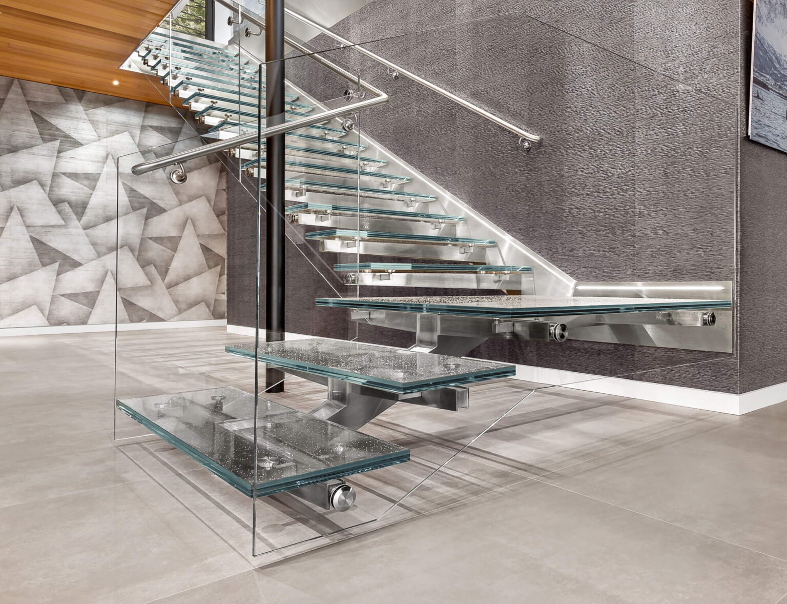 Glass staircase with laminated glass stair treads, metal frame and handrails