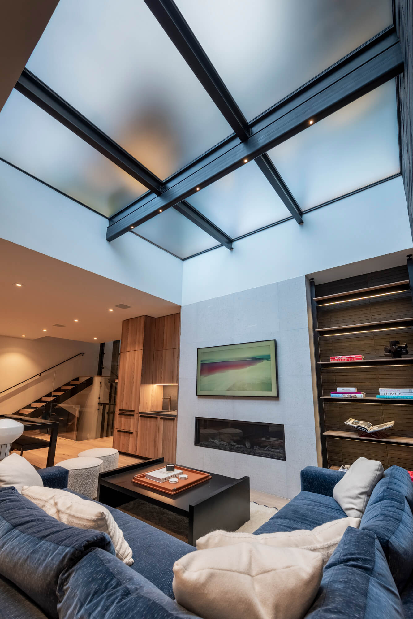 Below-grade living room viewed from below with a SkyFloor Series 1000 walkable skylight ceiling, satin Yorlux glass panels on black rafters bringing in daylight