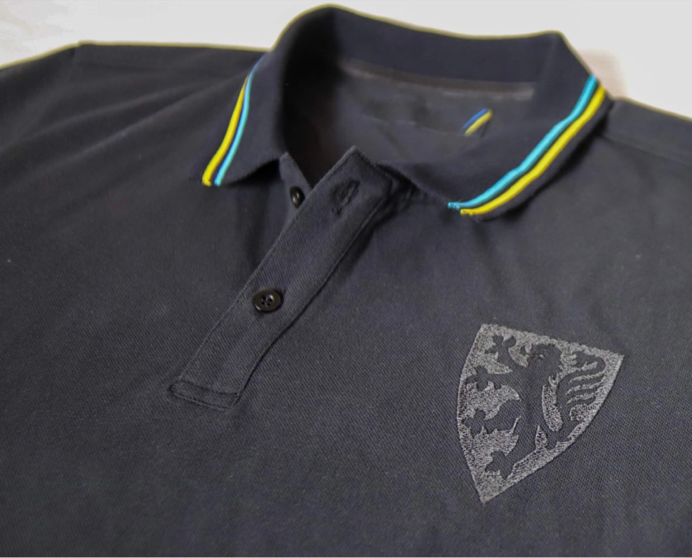 Produktfoto eines Polos mit Wappen-Druck und Kontrastkragen