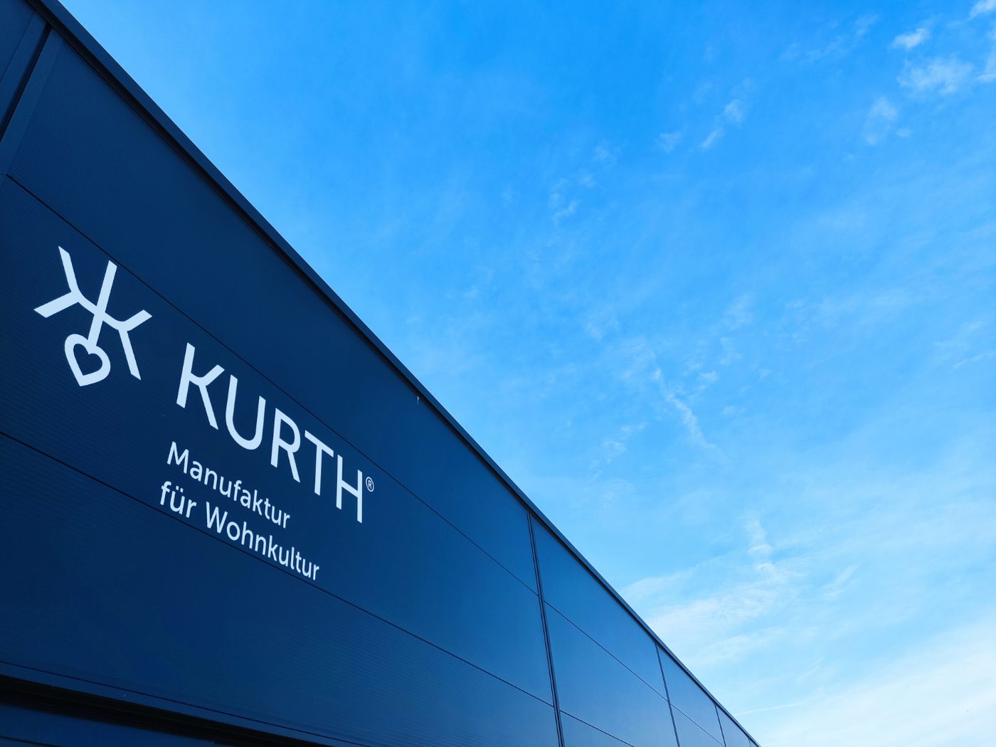 Fassade mit Logo-Beschriftung vor blauem Himmel