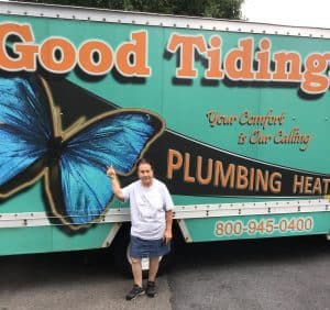 A person stands in front of a truck with a large blue butterfly and "Good Tidings Plumbing Heating" branding on the side.