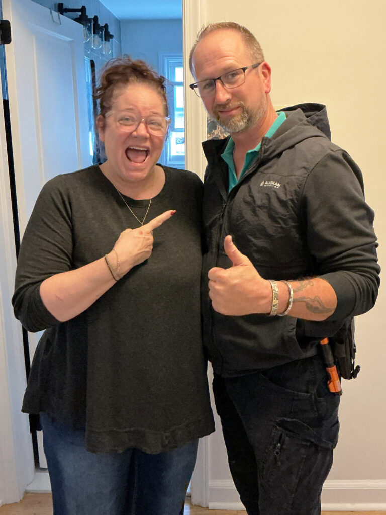 A man and woman smiling and pointing at something.