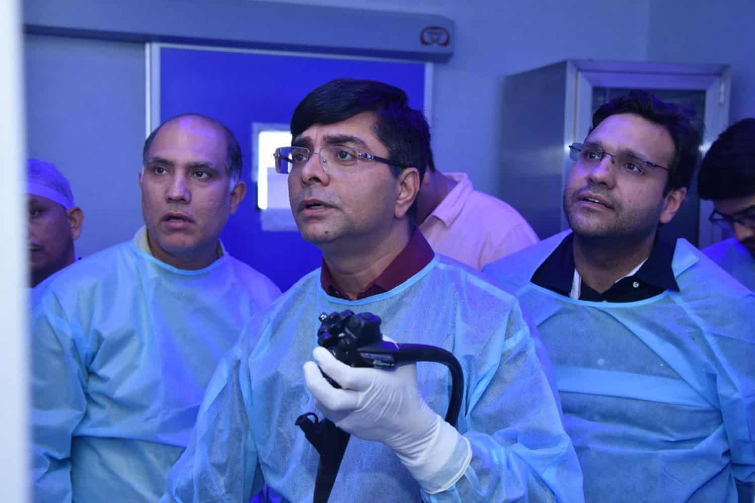 Dr. Rajiv Grover conducting a medical procedure with team in a clinical setting.