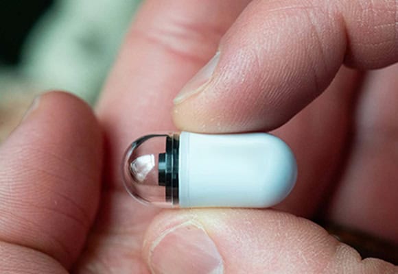 Close-up of a person holding a hearing aid device in their hand.