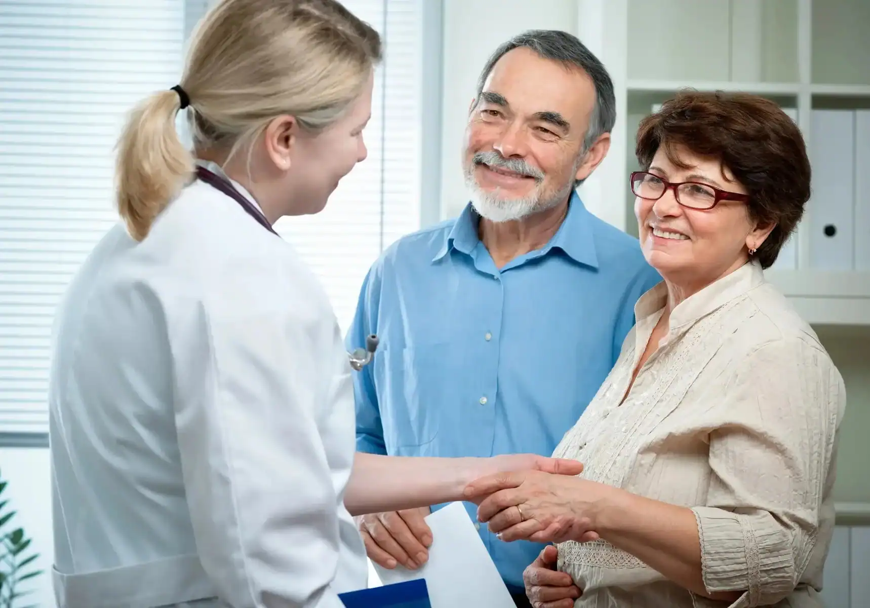 A doctor welcoming two smiling patients