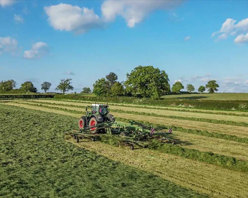 Tractor harvesting in a lush green field.