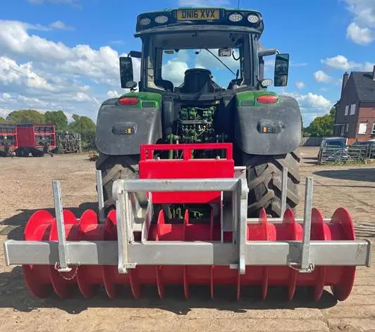 Tractor with red agricultural equipment attachment.