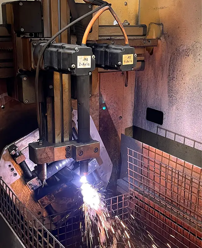 Industrial machine cutting metal with sparks flying.
