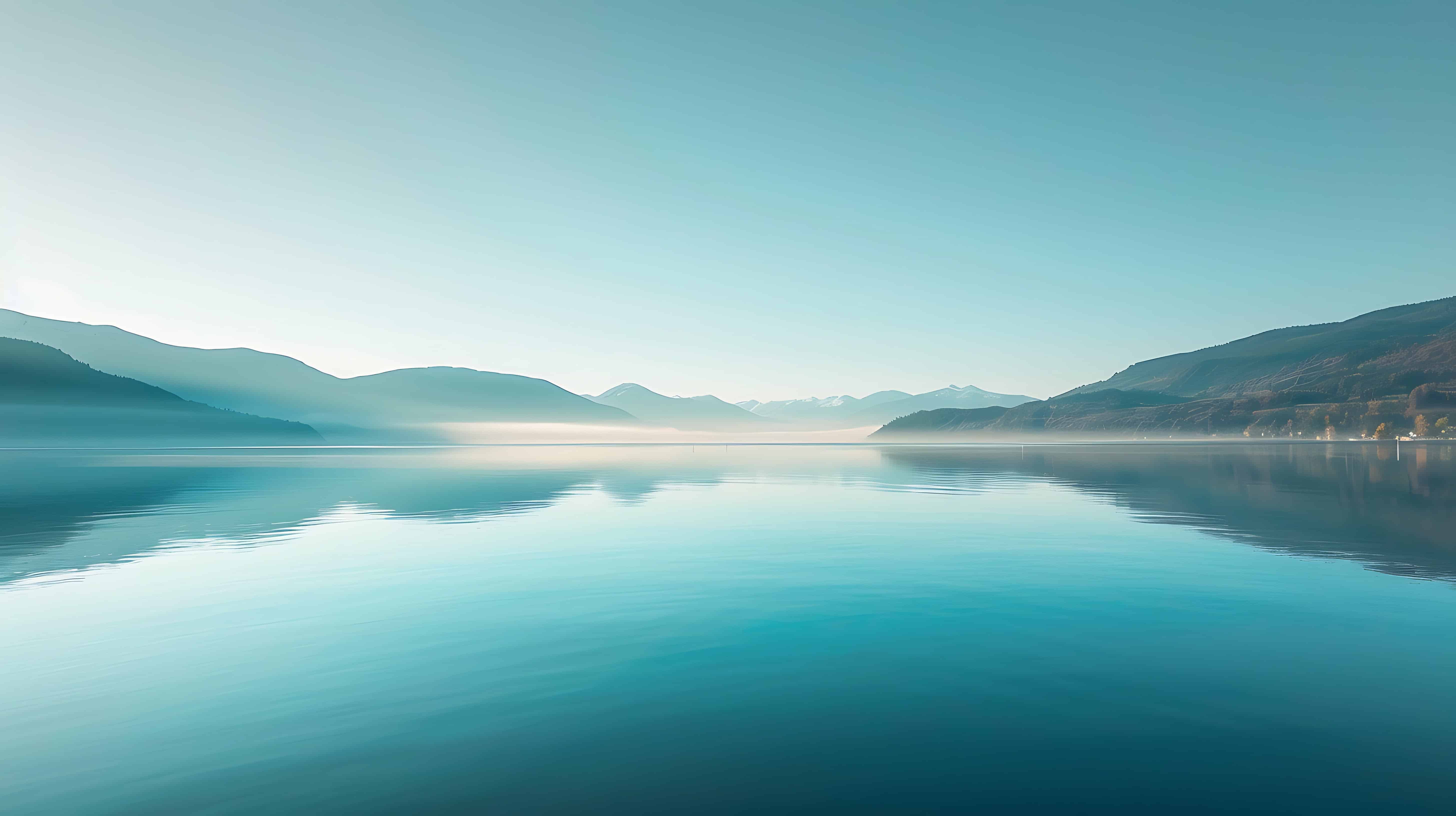 Tranquil lakeside view with glassy water mirroring sky and distant mountains