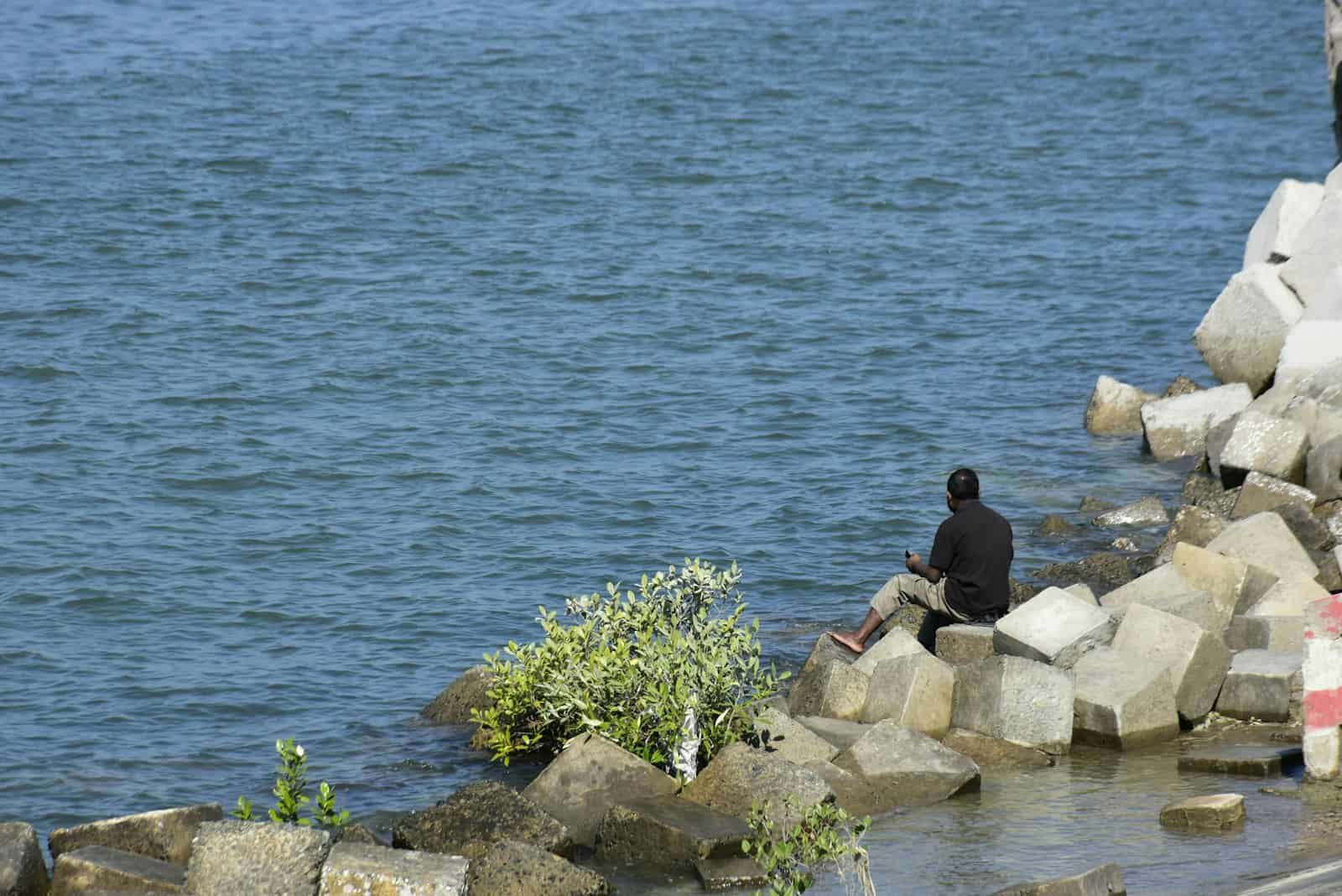 Angler sitting by the water observing conditions before casting