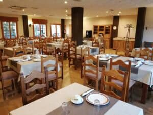Conjunto de mesas preparado para desayuno en hotel rural Villa de Vinuesa, ambiente acogedor y decorado en madera.