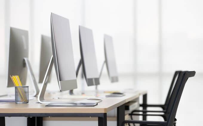 Modern office with multiple computers and chairs for IT team collaboration.
