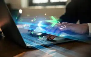 Person using a laptop with digital data transfer graphics overlay.