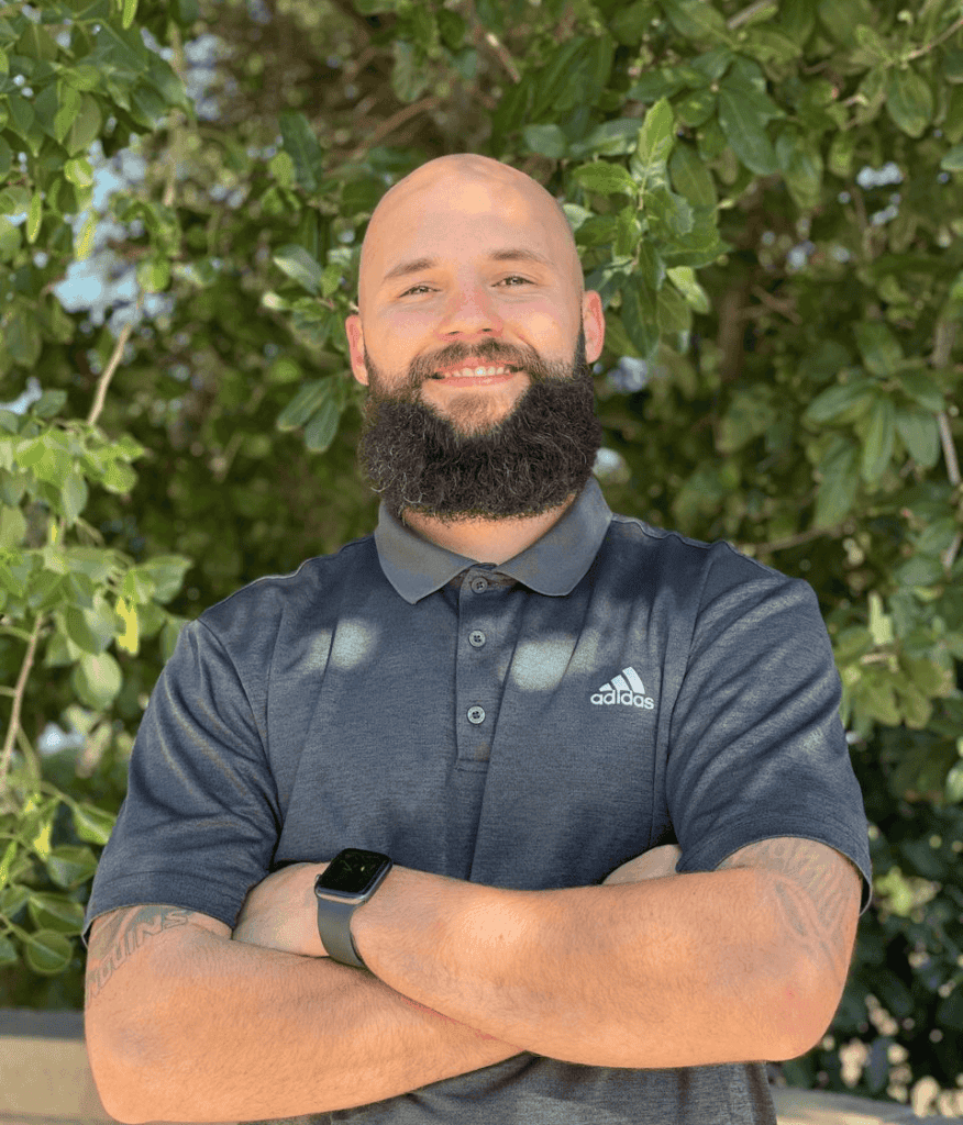 Impact Physical Therapy team member smiling outdoors with arms crossed.