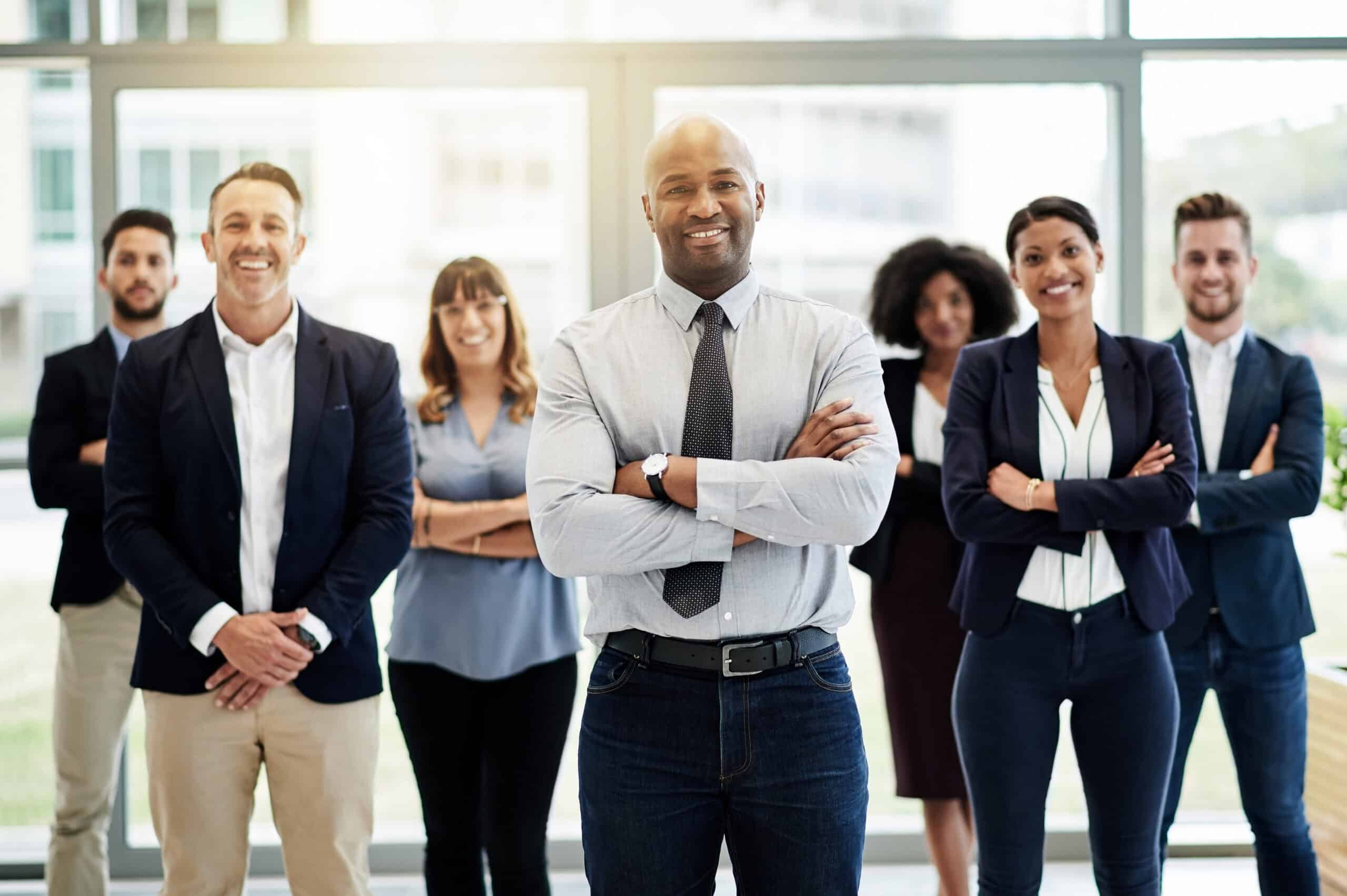 Diverse professional team confidently standing indoors with arms crossed.
