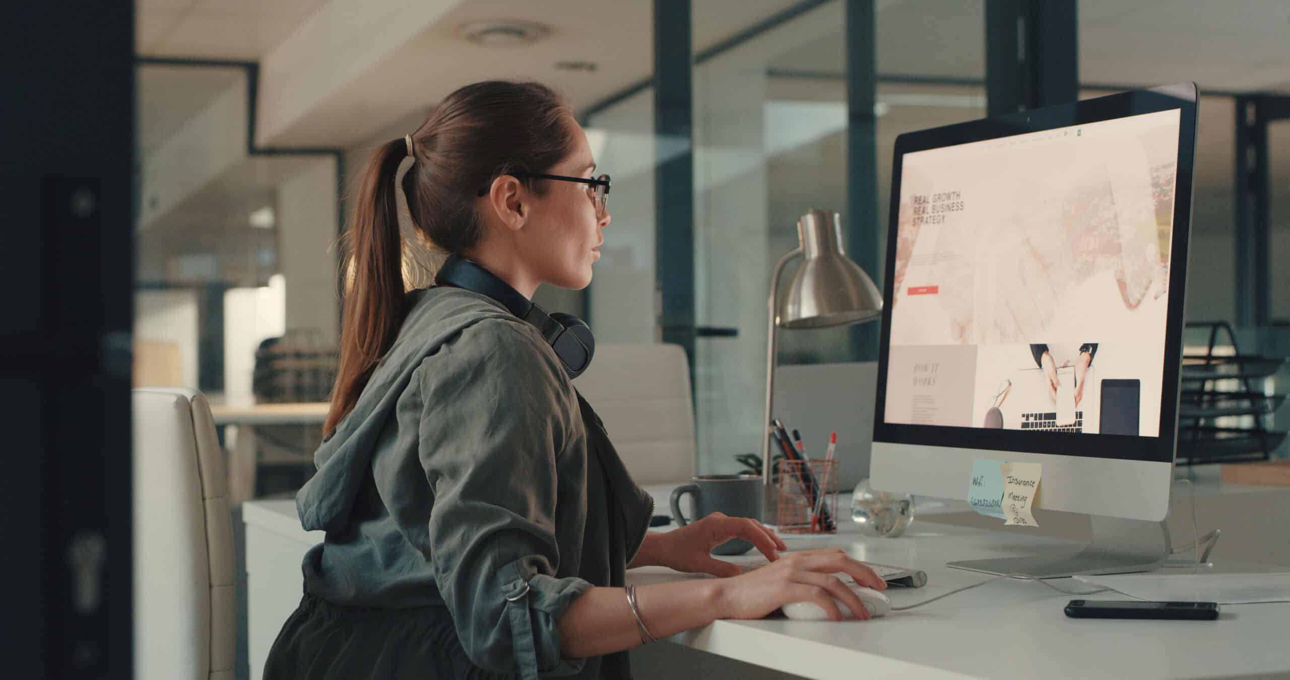 Female professional focused on work at desktop computer in contemporary workspace.