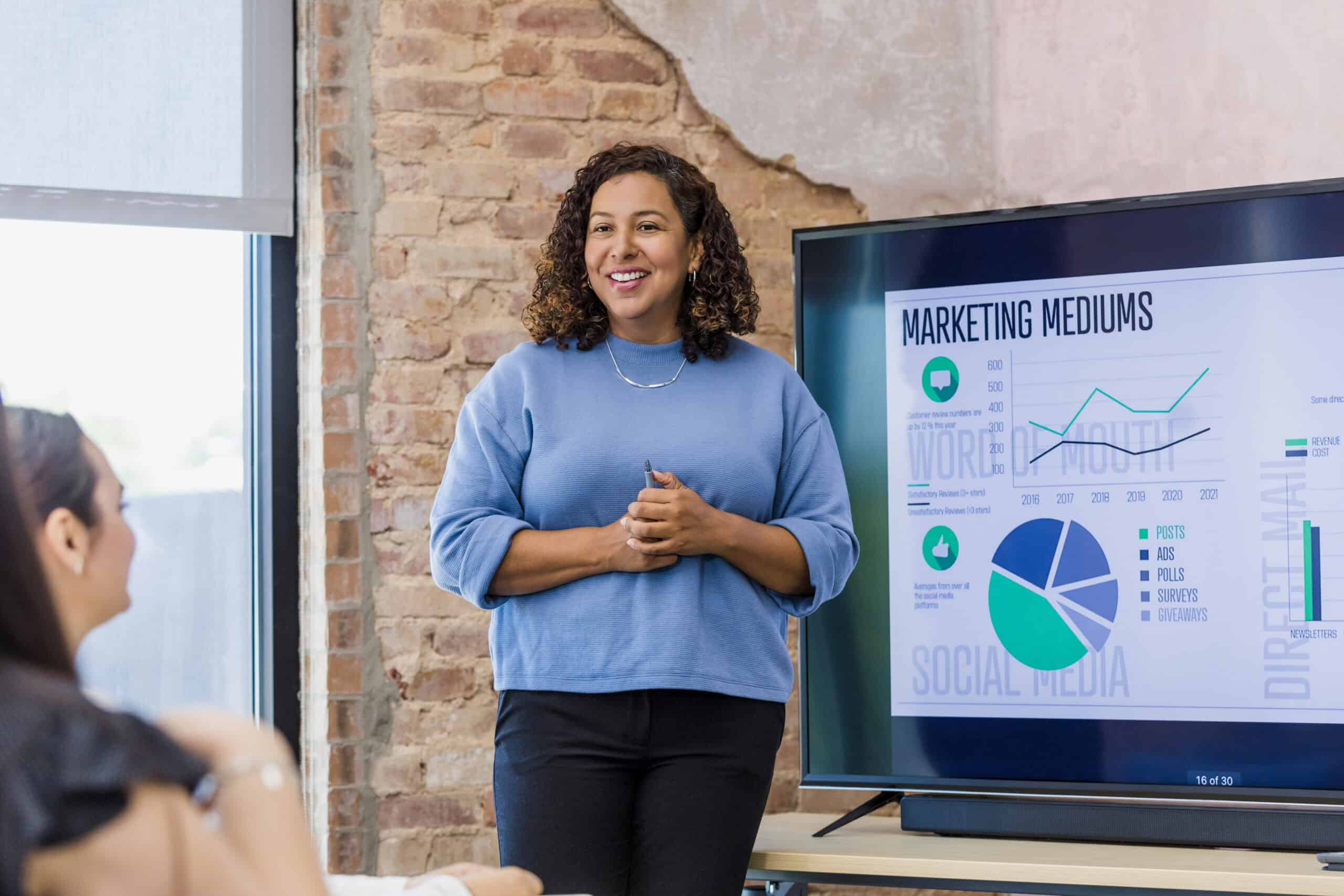 A woman presents marketing data with charts and graphs in a modern office space emphasizing independence and business success.