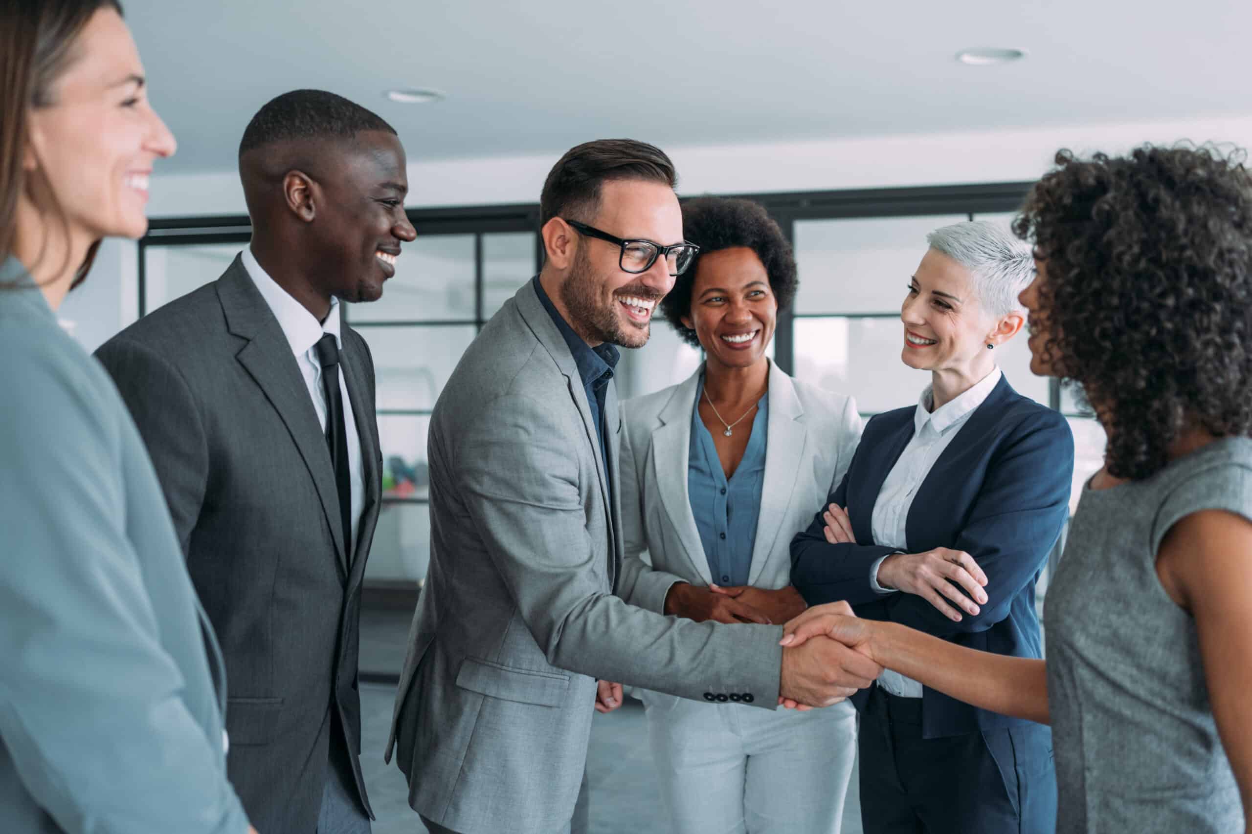 Diverse business team shaking hands during a professional meeting, showcasing independence and unity in the workplace.