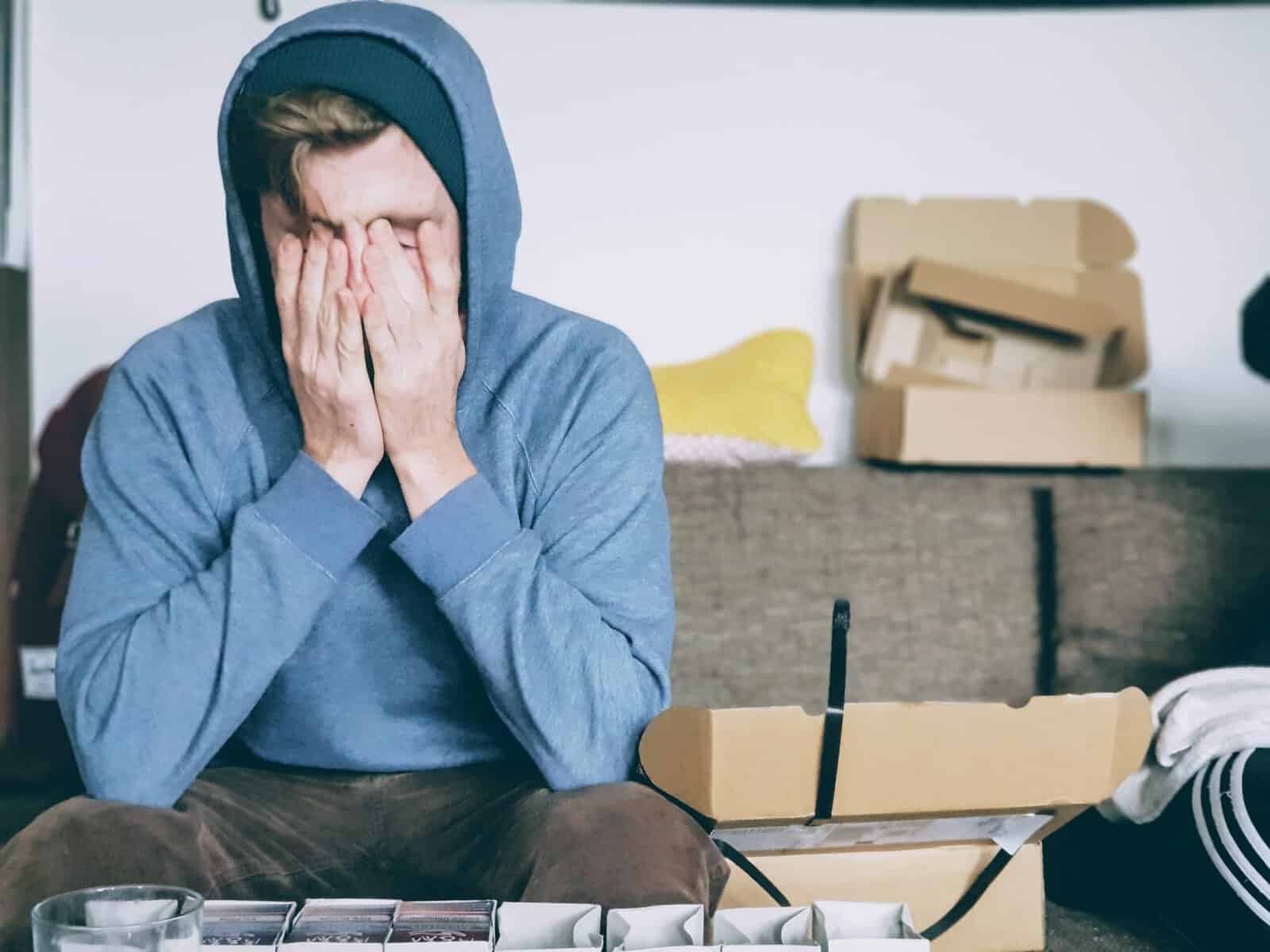 Man sitting on a couch rubbing his eyes, representing stress and fatigue from autoimmune disease