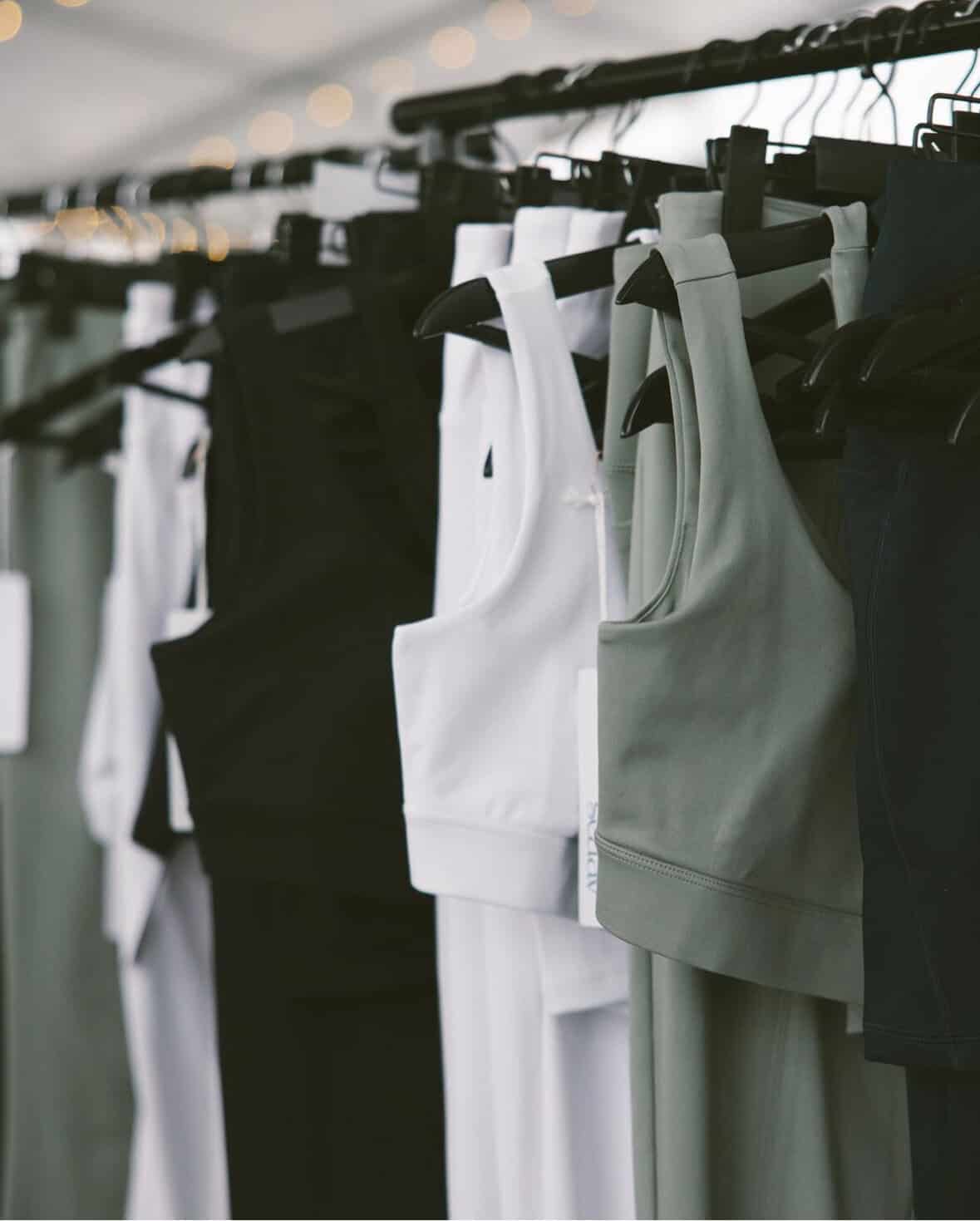 Sports bras hanging on a clothing rack in various colors and styles.