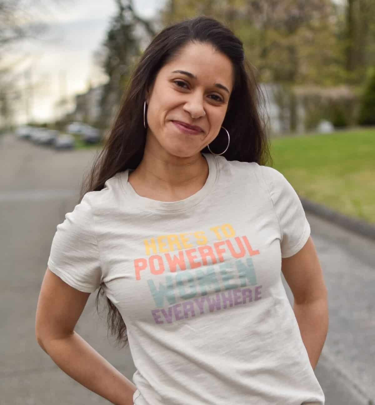 Woman smiling outdoors wearing a motivational t-shirt about empowerment.